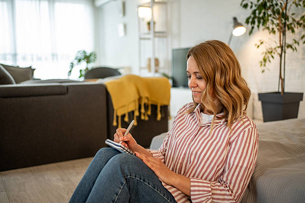 istock Woman taking notes while sitting on floor in living room 2213658039