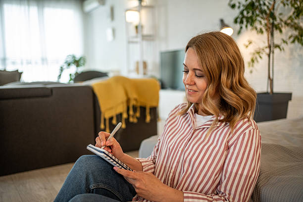 istock Woman sitting on floor taking notes in notebook at home 2213658043