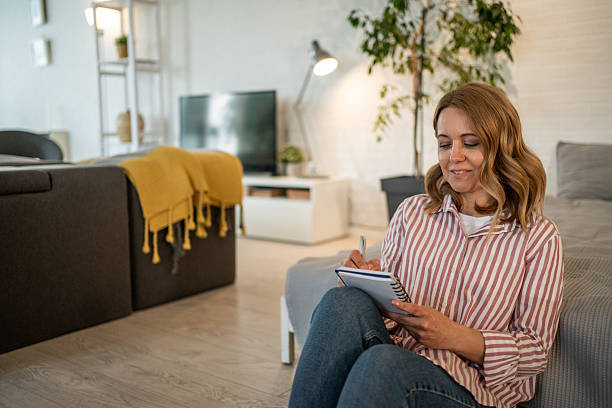 istock Woman sitting on floor taking notes in notebook at home 2213658051