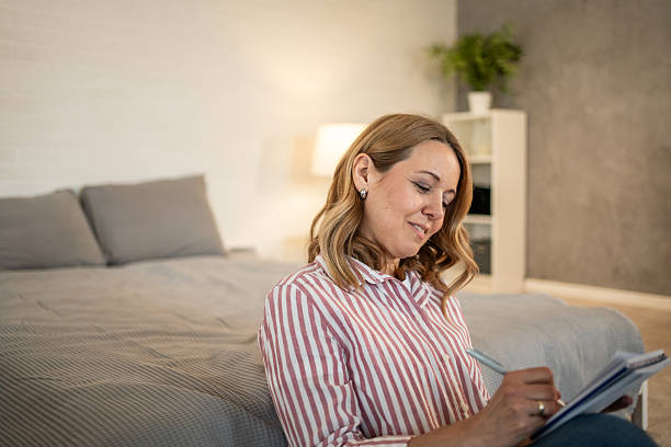 istock Woman writing on notebook sitting on bedroom floor 2213658071
