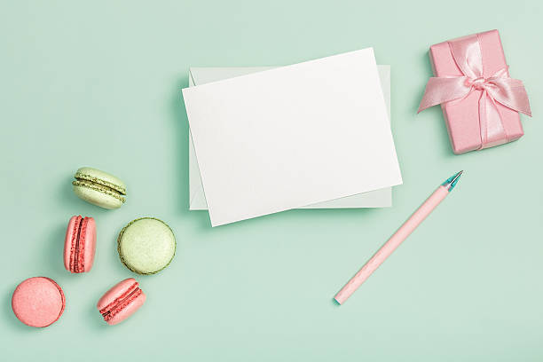 istock Flat lay composition with empty blank, pink gift box and colorful macaroons on light green background. Greeting card. Invitatio 2213658438