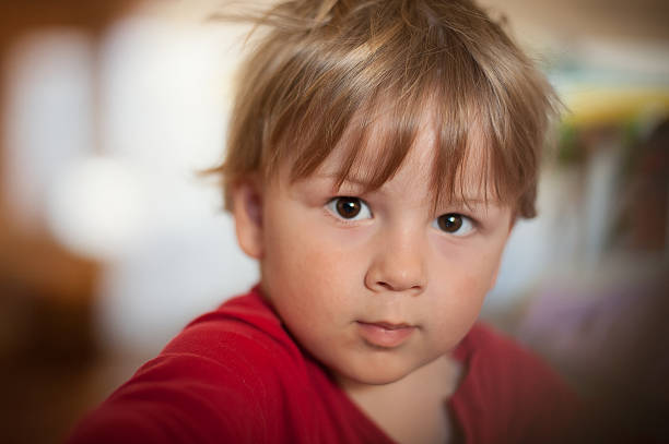 istock Young child with short brown hair exploring indoors with an inquisitive expression during daytime 2213658580