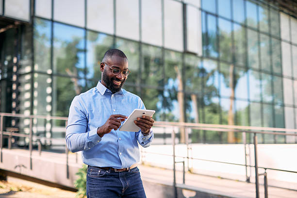 istock Smiling businessman using digital tablet in front of modern office building 2213659008