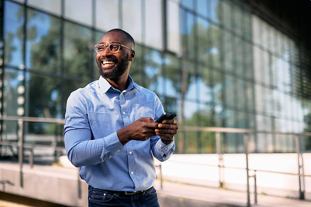 istock Smiling businessman using smartphone in front of modern office building 2213659010