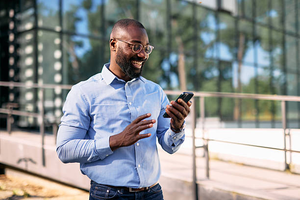 istock Smiling businessman using smartphone in front of modern office building 2213659016