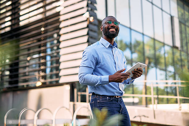 istock Smiling businessman using digital tablet outside modern office building 2213659042