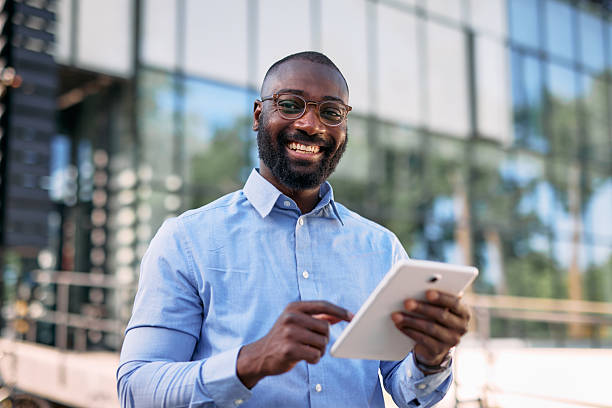istock Smiling businessman using digital tablet in front of office building 2213659043