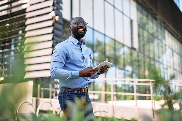 istock Smiling businessman using digital tablet outside modern office building 2213659056