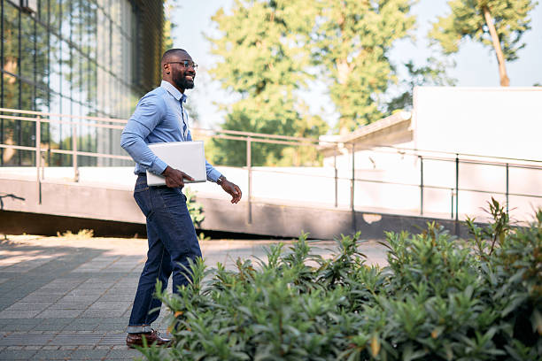 istock Smiling businessman walking outdoors carrying a laptop 2213659076