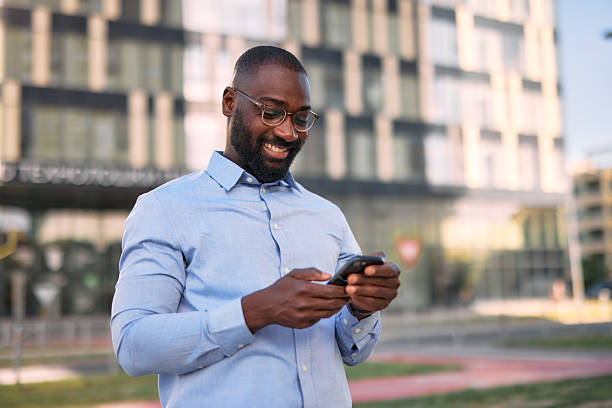 istock Smiling businessman using smartphone in front of office building 2213659209