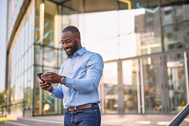 istock Smiling businessman using smartphone outside office building 2213659220