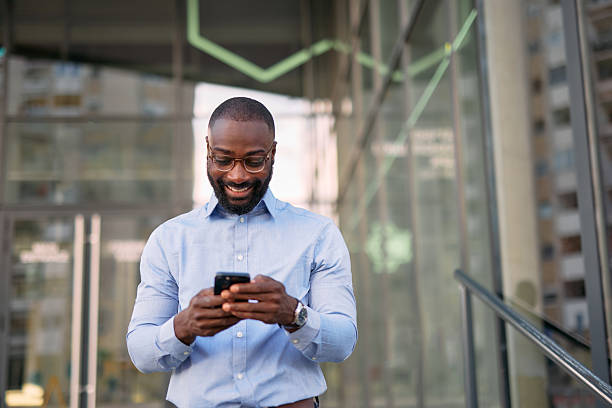 istock Smiling businessman using smartphone in front of office building 2213659221