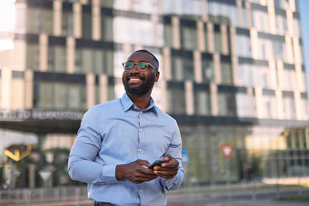 istock Smiling businessman using smartphone in front of office building 2213659223