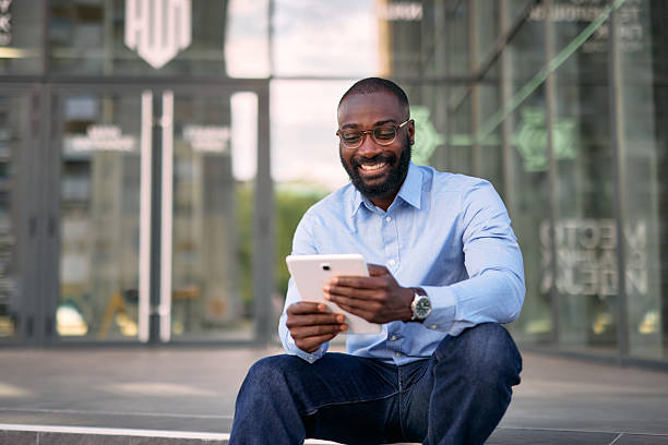 istock Smiling businessman using digital tablet sitting outside office building 2213659262