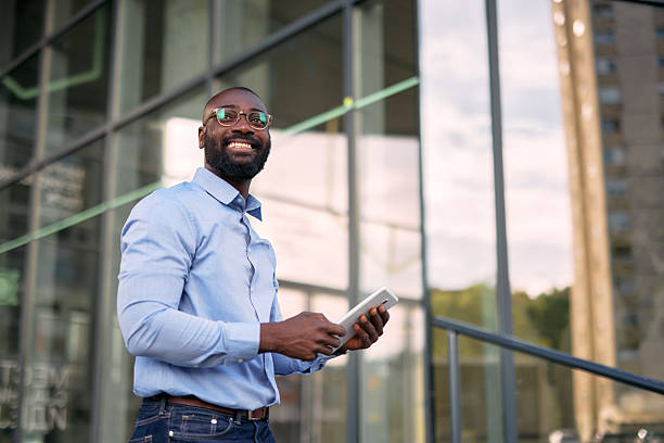 istock Smiling businessman using digital tablet in front of modern office building 2213659276