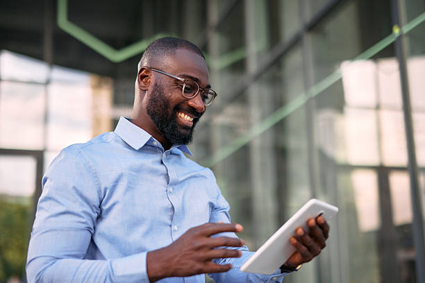 istock Smiling businessman using digital tablet in front of office building 2213659277