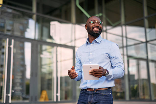 istock Smiling businessman using digital tablet and looking away near office building 2213659281