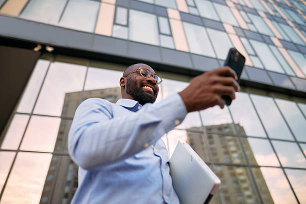 istock Smiling businessman using smartphone in front of modern office building 2213659314