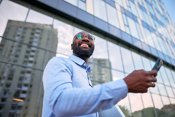 istock Smiling businessman using smartphone in front of modern office building 2213659316