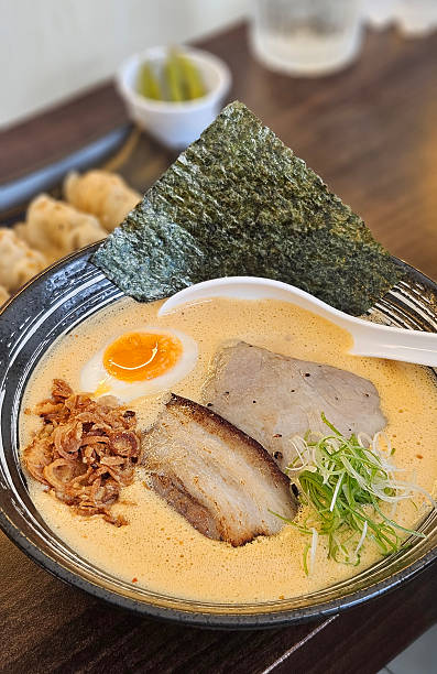 istock Spicy Ton Ton ramen in orange chilli soup serving with egg on black bowl 2213662044