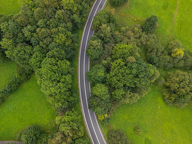 istock Curved road winding through lush greenery in a serene rural setting during the day 2213663935