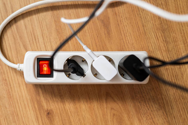 istock White power strip lying on wooden surface with multiple chargers and plugs connected, illuminated red power button indicating active electricity supply 2213664285
