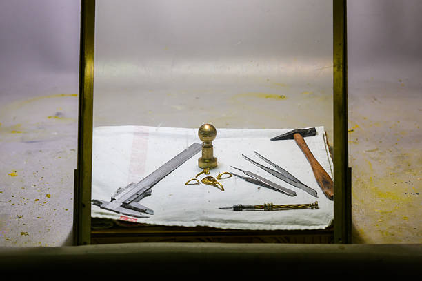 A collection of Eye brachytherapy preparation crafting tools, including pliers, hammers, and measuring instruments, placed on a cloth-covered workbench below a glass frame. The scene captures the precision of artisanal craftsmanship in a focused workspace, making it ideal for concepts of handmade artistry and tool organization in the crafting industry.