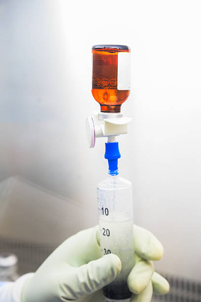 A healthcare worker wearing gloves draws a liquid substance from a brown medical vial using a syringe. The setup is clean and sterile, likely for medical or laboratory use. This process highlights the precision and care required in medical and pharmacological environments, particularly for treatments or research applications.