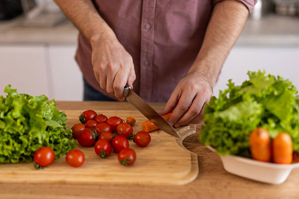 istock Man chopping vegetables in a kitchen, preparing ingredients for a meal. He is focused on the task, enjoying the process of cooking, with a relaxed and organized kitchen environment. 2213668030