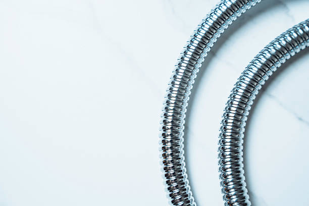 Shiny Flexible Shower Hose on Bathroom Background with Copy Space