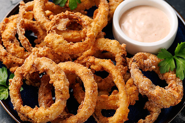 istock Homemade deep fried onion rings on plate with sauce. 2213668098