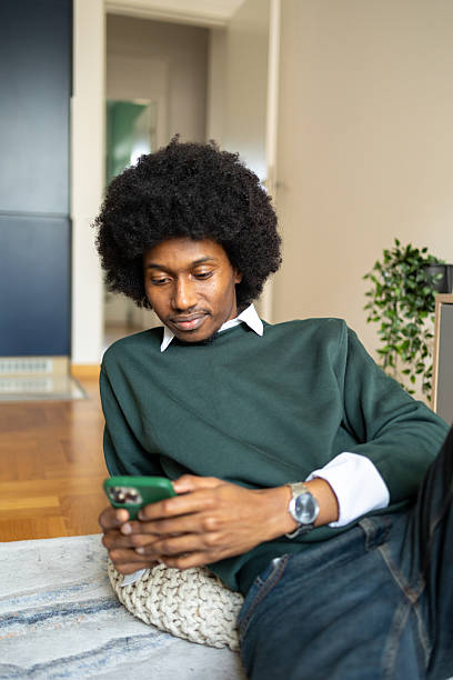 istock Relaxed man sitting and looking at smartphone while lounging indoors 2213670096