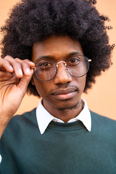 Young man adjusting glasses with focus on expression and thoughtful look. Looking at the camera