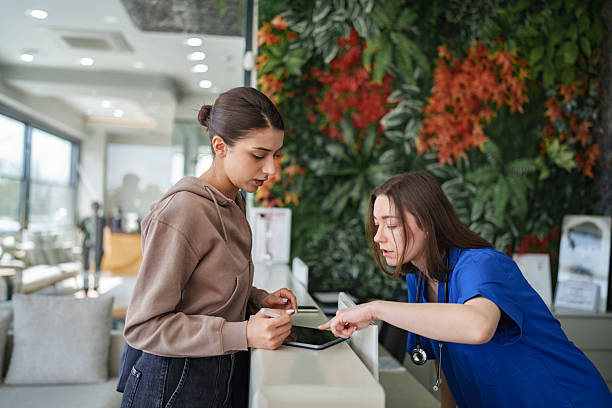 istock Female Patient Filling Out Digital Form at Front Desk 2213670251