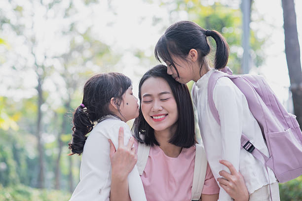 istock Mother sharing joyful moment with her two daughters in a sunny park setting surrounded by greenery 2213671546