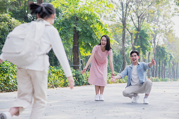 A warm, sunny afternoon finds a girl running joyfully toward two smiling friends in a vibrant park. The lush greenery creates a lively backdrop for their heartfelt reunion.