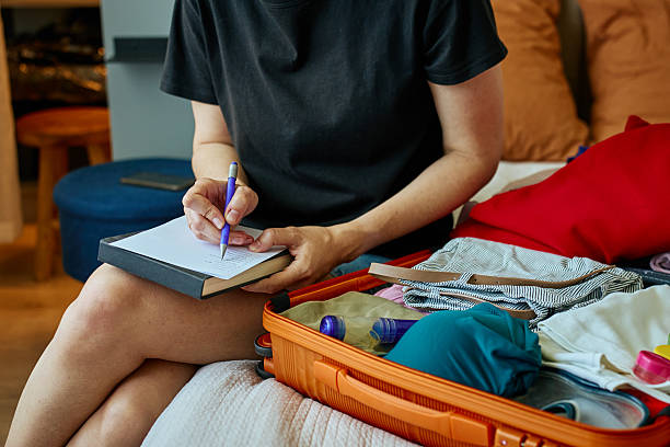 istock Woman packing suitcase and writing travel checklist 2213672171