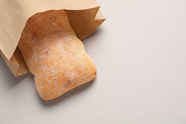 istock Paper bag with fresh ciabatta on beige background, top view. Space for text 2213672429