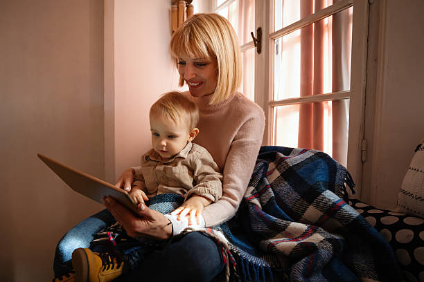 istock Smiling little boy with single mother having fun with tablet together. Technology, game, video 2213672485
