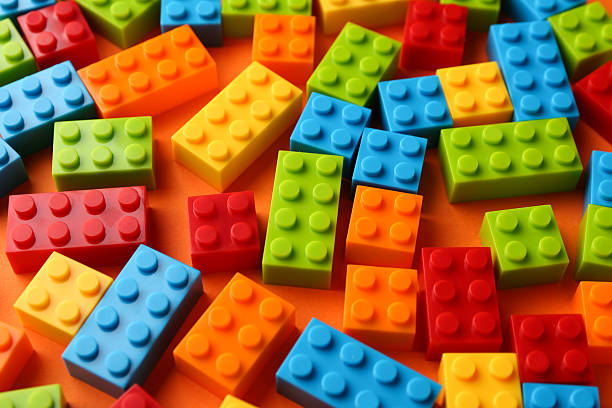 istock Construction toy. Colorful building bricks on orange background, closeup 2213672776