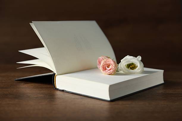 istock Open book with beautiful flowers on wooden table, closeup 2213672846