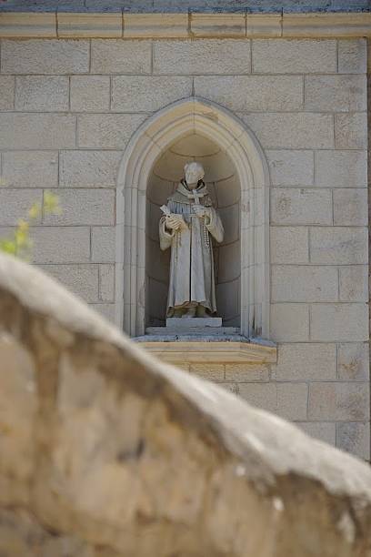 istock Stone monk statue in an arched niche on a brick wall. 2213673681