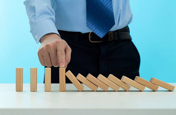 istock Businessman hand stopping the dominos falling 2213673943