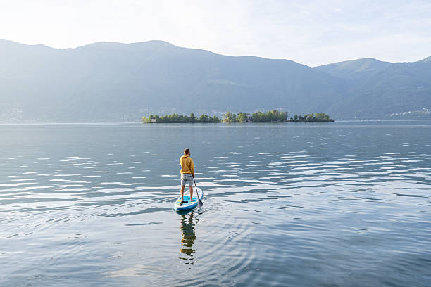 Young adult woman in wetsuit paddleboarding at lake