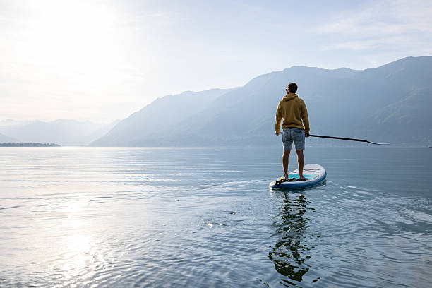 istock Man Paddleboarding on Serene Lake at Sunrise 2213675130