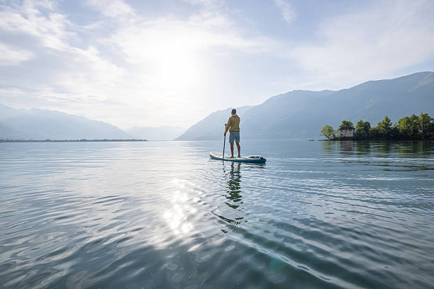 istock Person Paddleboarding on Serene Mountain Lake at Sunrise 2213675408