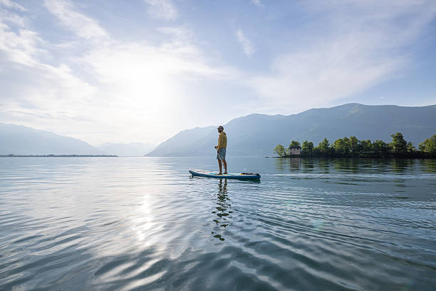 istock Person Paddleboarding on Serene Mountain Lake at Sunrise 2213675411