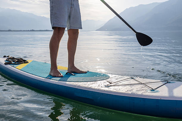 istock Person Paddleboarding on Serene Lake at Sunrise 2213675525