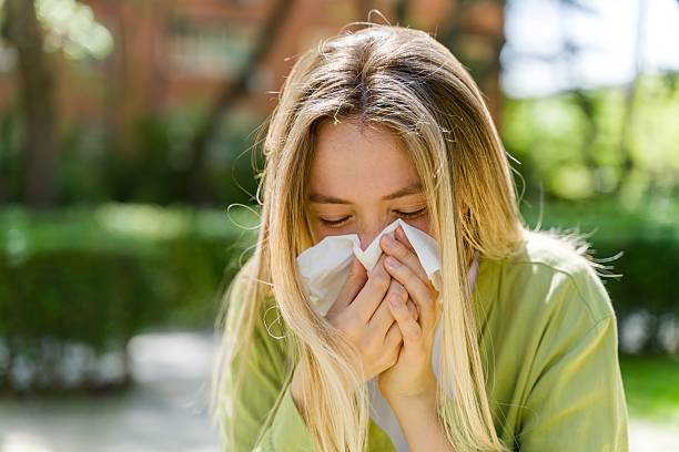 istock Young Woman Sneezing in a Green Park Setting 2213677361