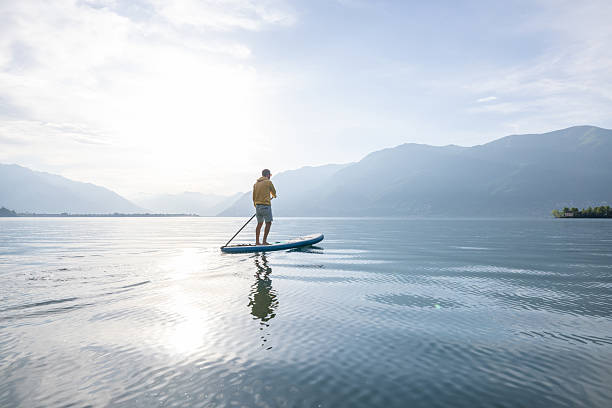 istock Man Paddleboarding on Serene Lake at Sunrise 2213678590